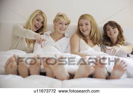 Stock Image - Four sisters laughing about their bare feet. Fotosearch