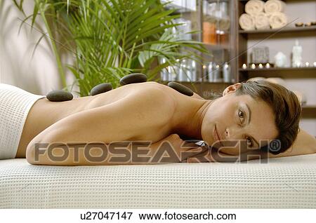 Hot stone massage - woman on the massagebed View Large Photo Image Stock Photo - Hot stone massage - woman on the massagebed. Fotosearch