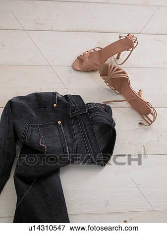 Stock Photo - Jeans and court shoes lying on wooden floor. Fotosearch