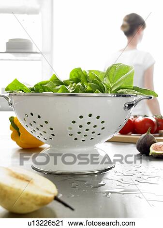 Stock Image - lettuce in a colander, woman in background. Fotosearch