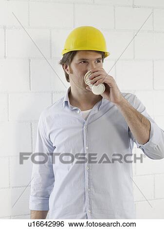 Stock Photograph - Man wearing a helmet is drinking coffee. Fotosearch