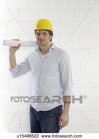Stock Image - Mann waering a helmet with a paper roll. Fotosearch
