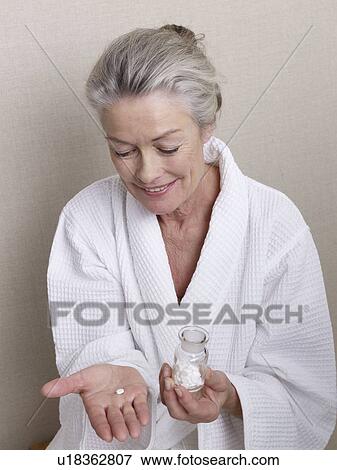 Stock Photo - Senior citizen in bath robe taking pills. Fotosearch
