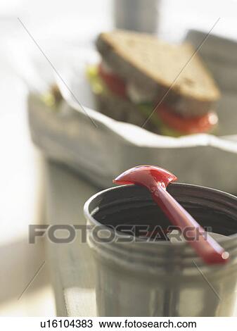 Stock Image - Tea in a thermos flask lid with a spoon. Fotosearch