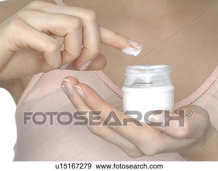Stock Photo - Teenage girl applying cream to her skin. Fotosearch