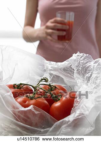 Stock Photograph - Tomatoes and woman with a glass of tomato juice. Fotosearch