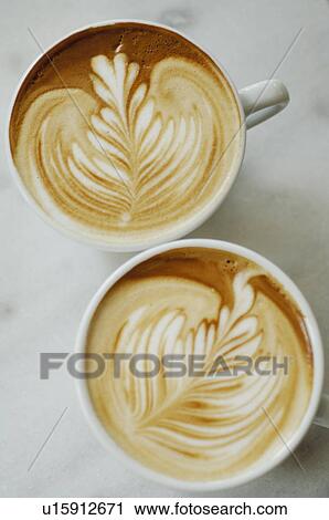 Stock Image - Two cups of white coffee with nice pattern. Fotosearch