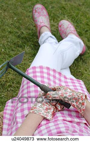Stock Image - Woman having a break from gardening. Fotosearch