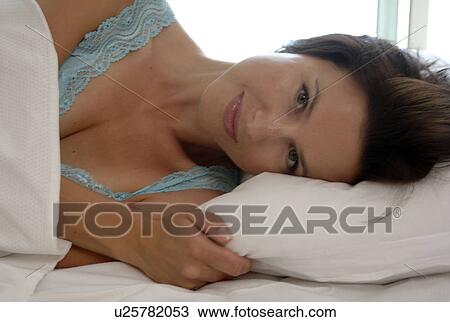 Stock Image - Woman in bed with pillow. Fotosearch
