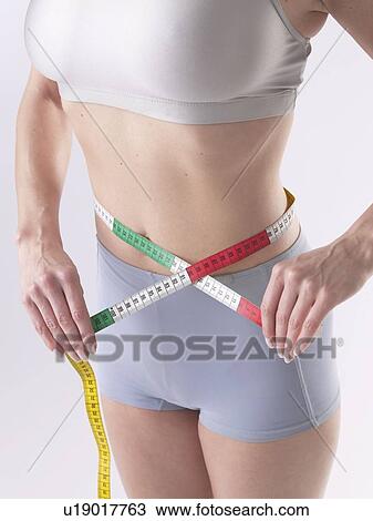 Woman is measuring her waist View Large Photo Image Stock Image - Woman is measuring her waist. Fotosearch