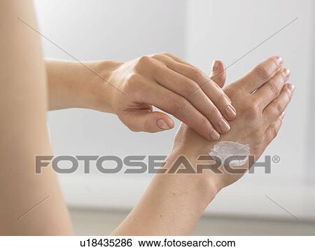 Stock Photograph - Woman is putting lotion on the back of her hand. Fotosearch