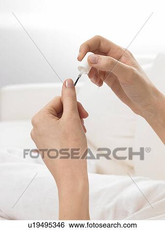 Stock Photograph - Woman is varnishing her nails. Fotosearch