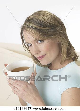 Stock Photo - Woman on the sofa drinking a cup of tea. Fotosearch