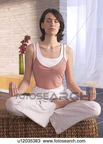 Stock Image - Woman sitting cross-legged doing yoga exercise. Fotosearch