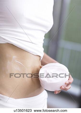 Stock Image - Woman with cream pot (close-up). Fotosearch
