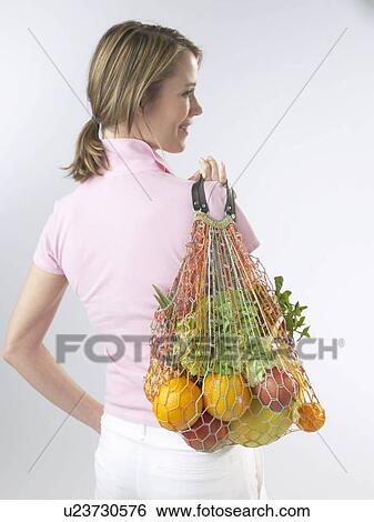 Woman with fruit and vegetables in a string bag View Large Photo Image Stock Photograph - Woman with fruit and vegetables in a string bag. Fotosearch