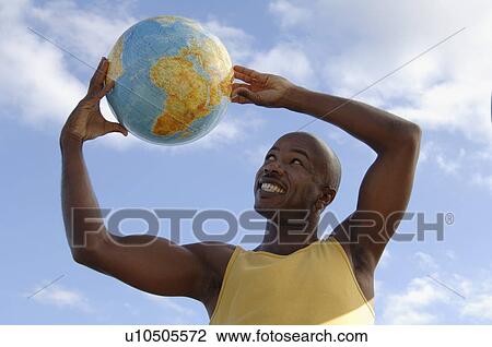 Young African Descent on the beach lifting a terrestrial globe over his head View Large Photo Image Stock Image - Young African Descent on the beach lifting a terrestrial globe over his head. Fotosearch