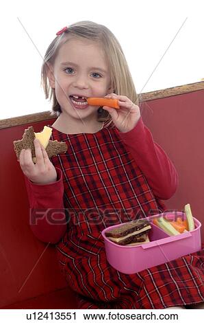 Young girl eating vegetables and brown bread from a lunch box View Large Photo Image Stock Image - Young girl eating vegetables and brown bread from a lunch box. Fotosearch