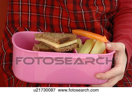 Young girl eating vegetables and brown bread from a lunch box View Large Photo Image Stock Photo - Young girl eating vegetables and brown bread from a lunch box. Fotosearch