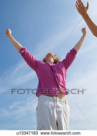 Young man on the beach raising his arms in the air View Large Photo Image Stock Image - Young man on the beach raising his arms in the air. Fotosearch