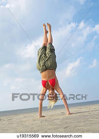 Young woman does a handstand on the beach View Large Photo Image Stock Photo - Young woman does a handstand on the beach. Fotosearch