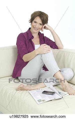 Stock Photography - Young woman sitting on sofa. Fotosearch