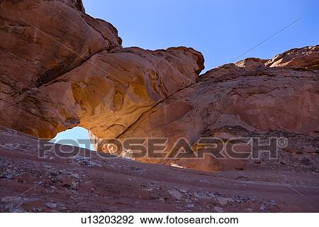 Stock Image - Arch formation backlit in early morning light, near Delicate Arch, Arches, Utah. Fotosearch