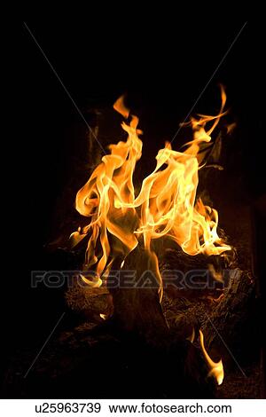 Stock Photo - Dancing flames of a camp fire at night, with metal pots in background, Utah. Fotosearch