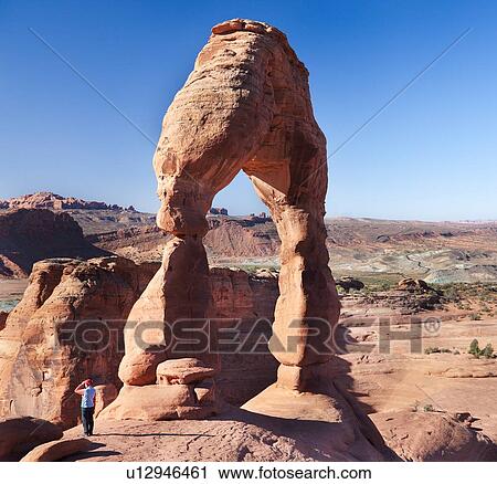 Delicate Arch in early morning sunlight against blue sky, single figure standing below, Arches, Utah View Large Photo Image Stock Image - Delicate Arch in early morning sunlight against blue sky, single figure standing below, Arches, Utah. Fotosearch
