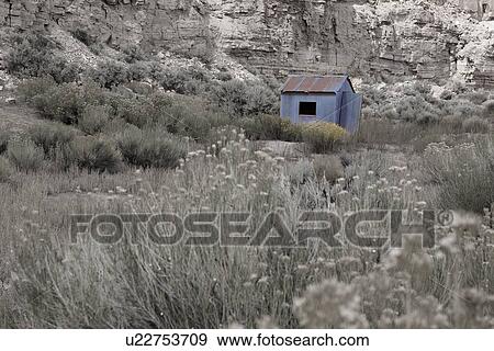 Stock Photo - Desaturated image of deserted blue hut (colour retained) with sage brush foreground against rock face backdrop, Utah. Fotosearch