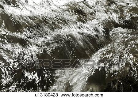 Stock Photo - Desaturated image of river flowing over rocks, motion slowed to capture linear highlights, and texture of water, Utah. Fotosearch