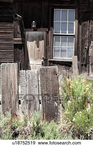 Stock Photo - Detail of wooden house with doorway, window overlooking garden and wooden picket fence, desaturated image, Bodie pioneer village, California. Fotosearch