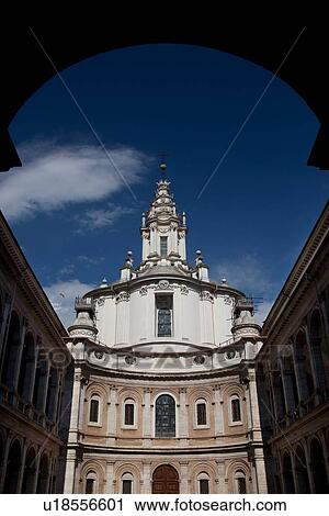 Stock Image - Facade of Sant'Ivo alla Sapienza, framed by silhouetted entrance archway in late afternoon sunlight. Fotosearch