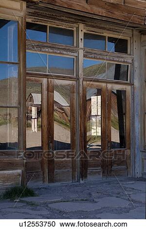 Main hotel doorway with glass reflection of wooden housing, hills and blue sky in early summer morning, Bodie pioneer village, California View Large Photo Image Stock Image - Main hotel doorway with glass reflection of wooden housing, hills and blue sky in early summer morning, Bodie pioneer village, California. Fotosearch
