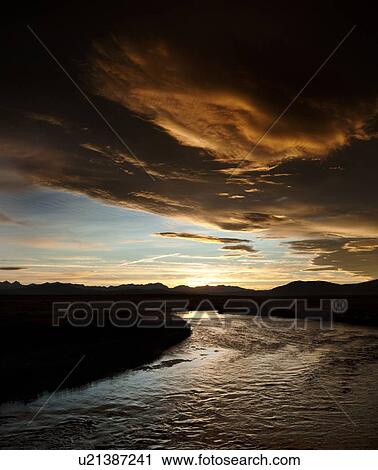 Stock Image - Owens River curving through grassy flatlands with dramatic lenticular clouds, black and orange, on a summer evening. Fotosearch