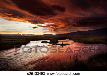 Owens River curving through grassy flatlands with dramatic lenticular clouds, black and pink, reflected in the water, on a summer evening View Large Photo Image Stock Image - Owens River curving through grassy flatlands with dramatic lenticular clouds, black and pink, reflected in the water, on a summer evening. Fotosearch
