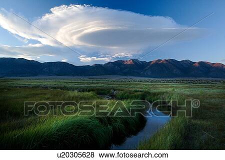 Owens River curving through grassy flatlands with dramatic white lenticular clouds, reflected in the water, and Sierra Nevada mountain range in distance, on a summer evening View Large Photo Image Stock Photo - Owens River curving through grassy flatlands with dramatic white lenticular clouds, reflected in the water, and Sierra Nevada mountain range in distance, on a summer evening. Fotosearch