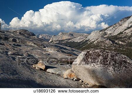 Stock Photograph - Panorama at Olmsted Point with erratics in foreground along granite ridge, and blue summer afternoon sky, with dramatic cloud formation, Yosemite. Fotosearch