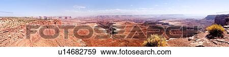 Stock Photo - Panorama of immense valley, Buck Canyon Overlook, with foreground bushes, extending miles to deep crevice formation, sunny fall morning, Utah. Fotosearch