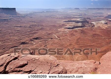 Stock Photo - Panorama view of Green River Overlook, stretching miles to deep winding crevice in valley, sunny fall morning, with blue sky and puffy cloud formation, Utah. Fotosearch
