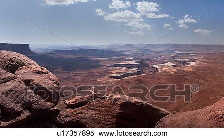 Stock Photography - Panorama view of Green River Overlook, stretching miles to deep winding crevice in valley, sunny fall morning, with blue sky and puffy cloud formation, Utah. Fotosearch
