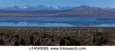 Stock Photo - Panorama view of Mono Lake, morning summer sun with snow-capped mountain range reflected in water. Fotosearch