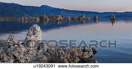 Stock Image - Panorama view of Mono Lake, with tufa formations, at dawn with pink light reflected against the purple hills of the background. Fotosearch