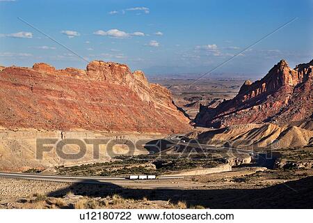 Panorama view of mountains and interstate highway winding through gorge, San Rafael Reef, at sunset with blue sky and puffy clouds, with white triple trailer transport truck on road, Utah View Large Photo Image Stock Image - Panorama view of mountains and interstate highway winding through gorge, San Rafael Reef, at sunset with blue sky and puffy clouds, with white triple trailer transport truck on road, Utah. Fotosearch