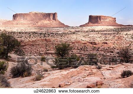 Stock Image - Panorama view of red rock Merrimac and Monitor buttes, Canyonlands, with blue sky, sunny fall morning, Utah. Fotosearch