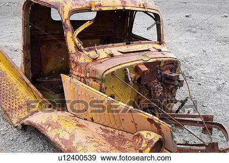 Stock Photo - Rusted hulk of antique yellow car abandoned in Reds Canyon, Utah, partially desaturated image. Fotosearch