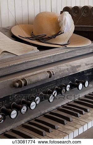 Picture - Schoolroom with original harmonium, view of dusty keyboard, straw hat placed on top, desaturated image, Bodie pioneer village, California. Fotosearch