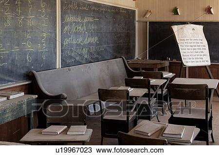 Stock Image - Schoolroom with original old desks and chairs, chalkboard, desaturated image, Bodie pioneer village, California. Fotosearch