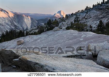 Stock Image - View of Half Dome in late afternoon summer sunlight, across granite trail, Olmsted Point, Yosemite. Fotosearch