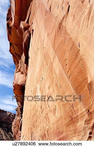 Stock Photograph - View of pictographs at Buckhorn Draw, Utah, painted rock with figures and snake, showing side of cliff and blue sky above, oblique view. Fotosearch